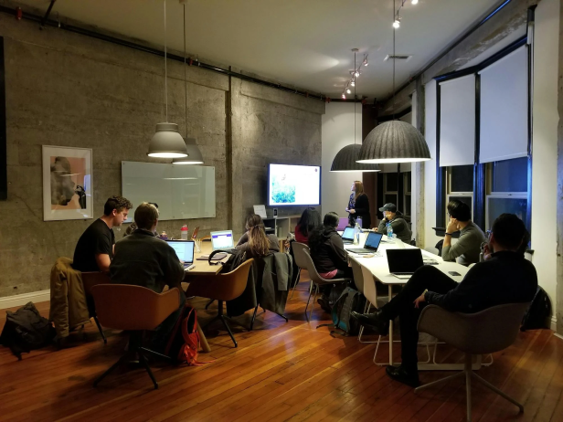 A group of people sitting around a table working on laptops.